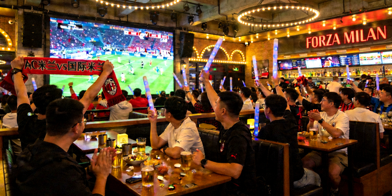 众多球迷在酒吧通过大屏幕观看AC米兰意甲比赛直播的热闹场景